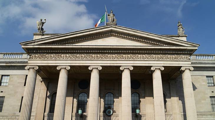 The facade of a Georgian structure with three statues on top and six columns