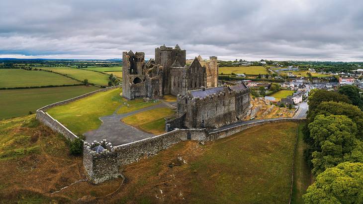 Aerial view of a medieval building complex on a hill surrounded by greenery