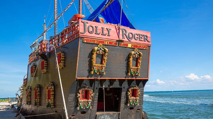 A pirate-themed dinner cruise with intricate windows docked by the blue sea