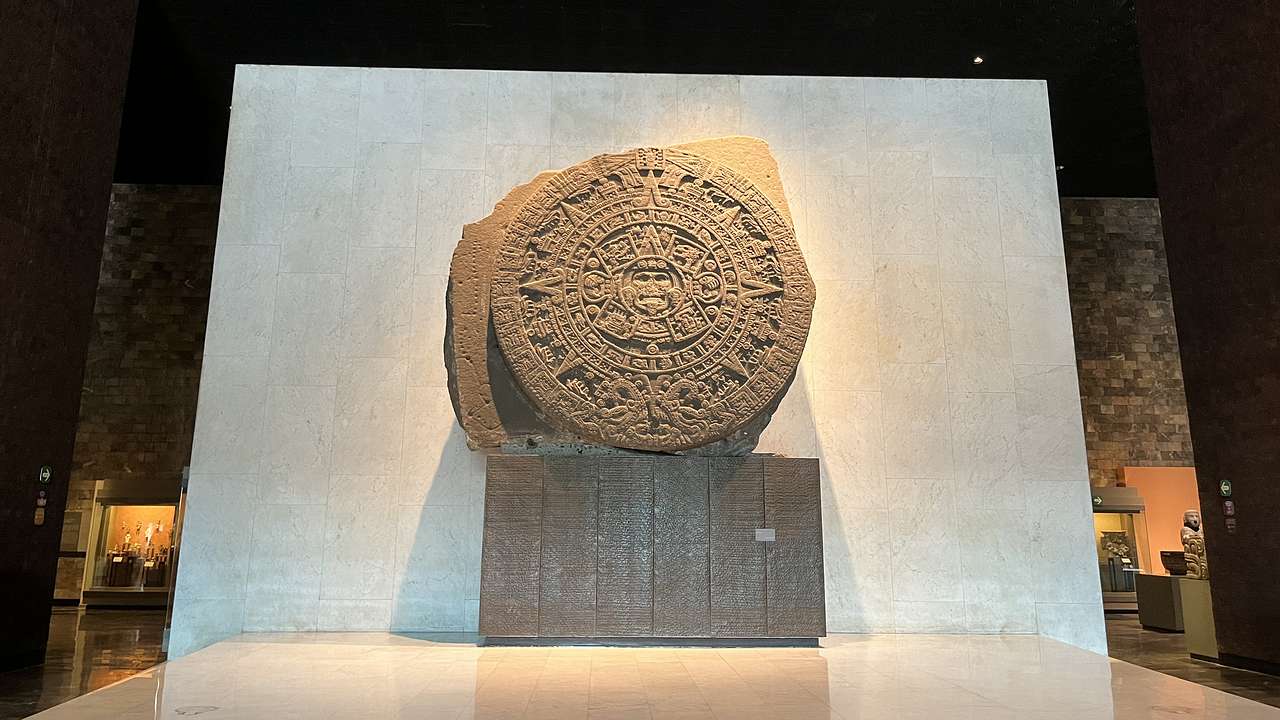 A round basalt disk with a face-like shape in the middle and a sun-designed border