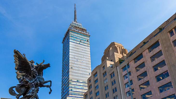 Looking up at a modern skyscraper and other structures against a clear sky