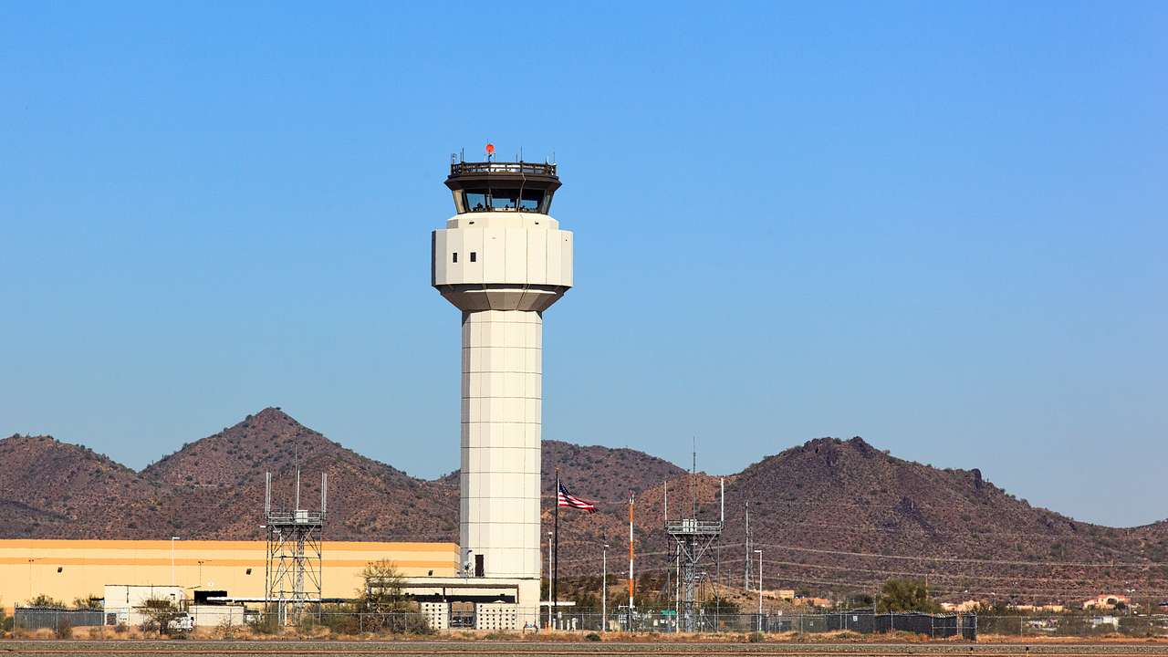 An airport control tower with a small mountain range in the background