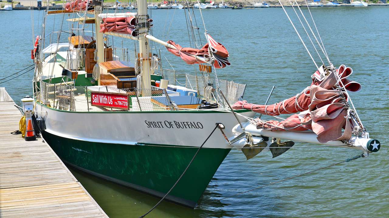 A green and white boat that says "Spirit of Buffalo" docked near a port