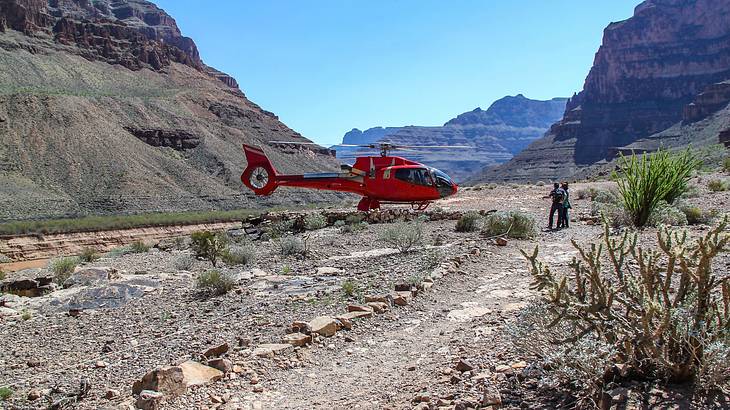 A helicopter landed in a canyon with mountains surrounding it