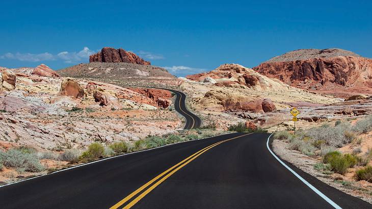 A road running through the desert with red mountains in the distance