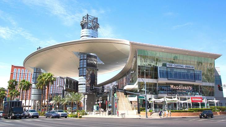 A shopping mall with signs for shops and restaurants and cars on the road in front