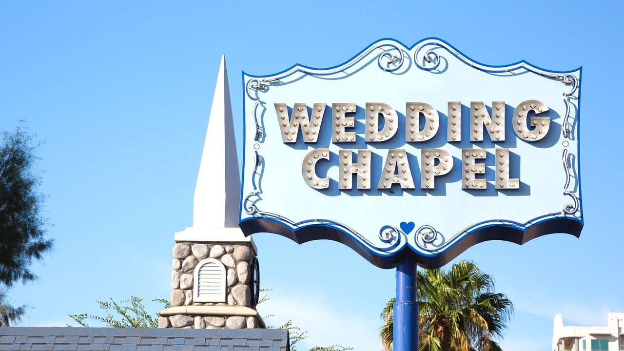 The spire of a chapel with a blue wedding chapel sign