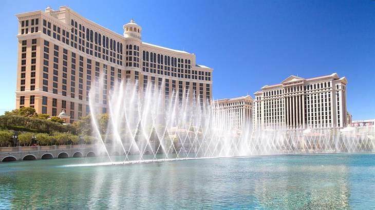 A water feature with spraying water and a hotel behind it