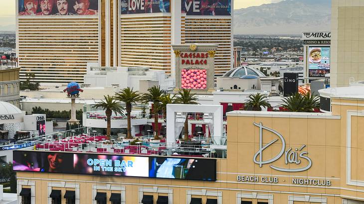 A building with nightclub sign and rooftop bar and buildings and mountains behind