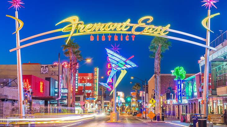 A street with colorful buildings, a neon street sign, and a neon martini glass