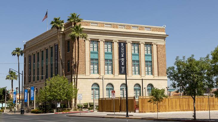 A two-floor square building with a flag on top, surrounded by trees and roadways