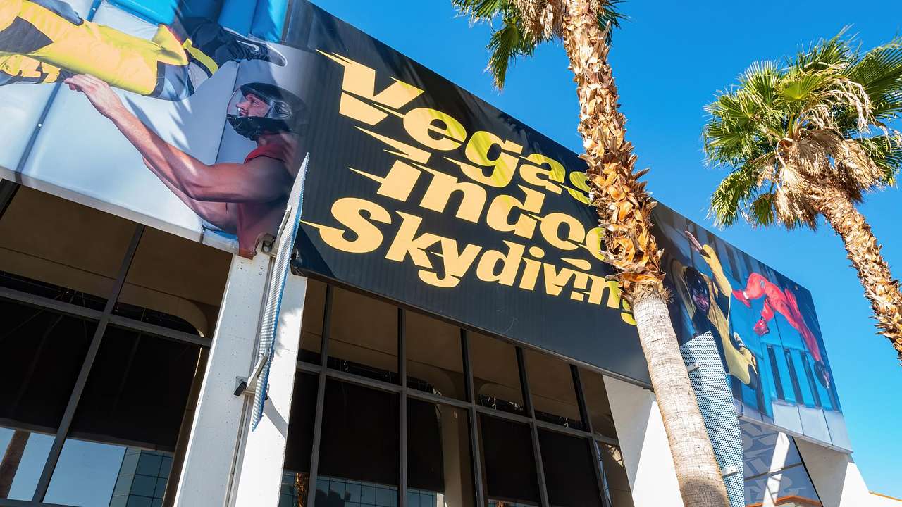 A building with a poster that says "Vegas Indoor Skydiving" next to palm trees
