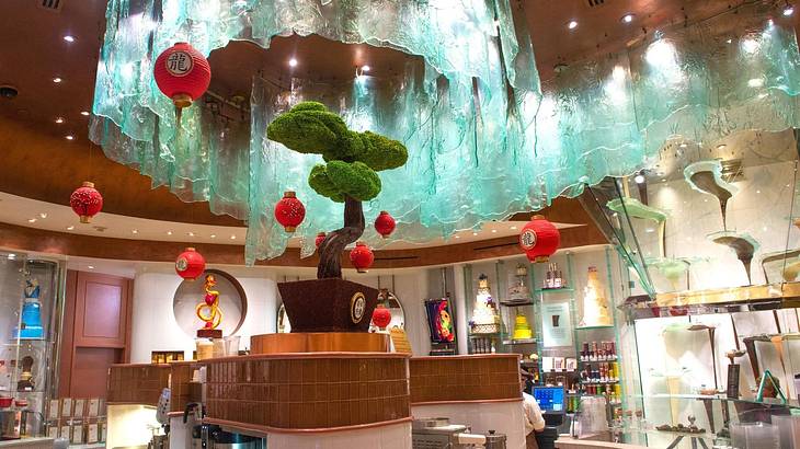 A cafe with a plant, lanterns, and a modern glass chocolate fountain