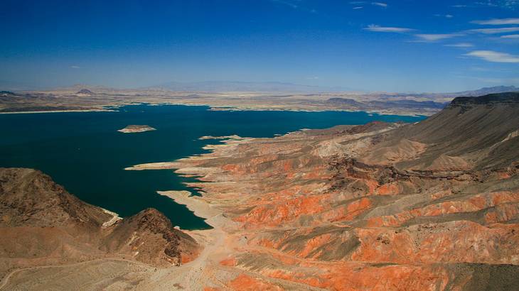 A reservoir with red rock mountains surrounding it under a blue sky