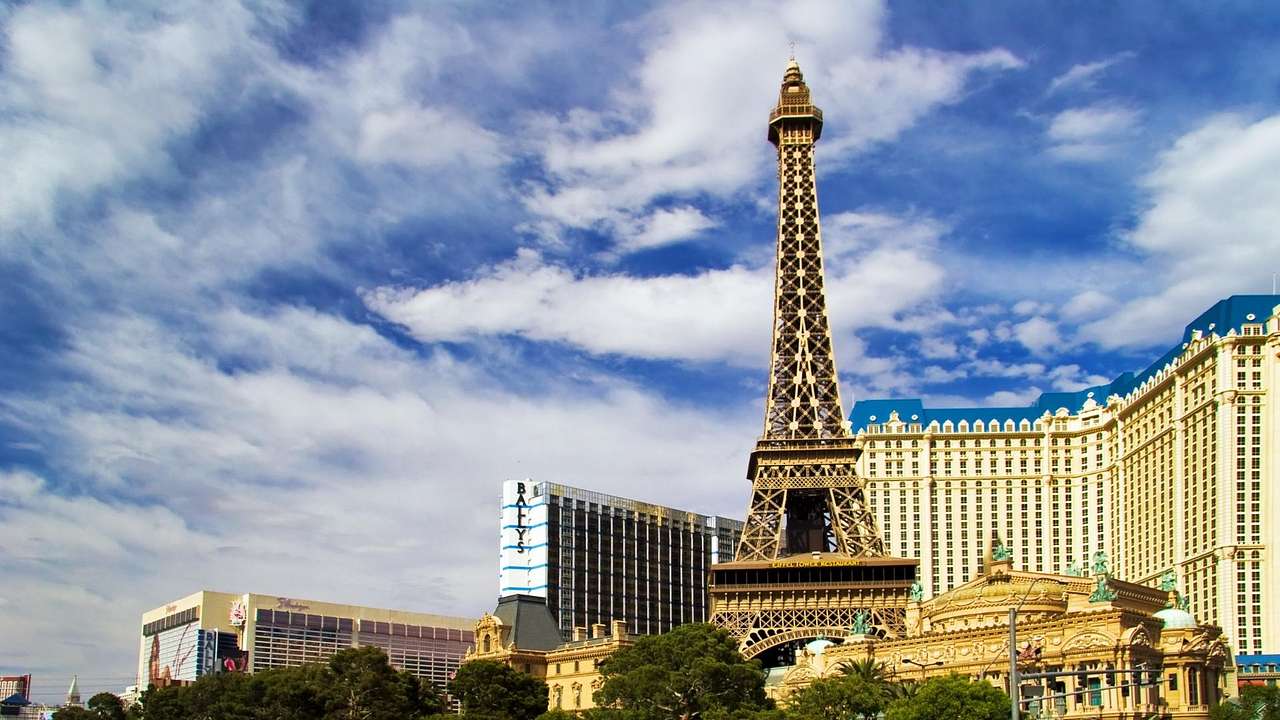 An Eiffel Tower replica with buildings surrounding it under a blue sky with clouds