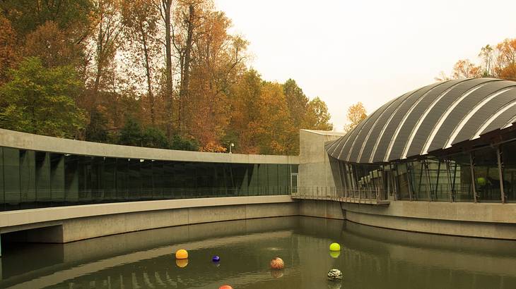 A pond filled with colorful balls in front of a modern concrete and glass structure