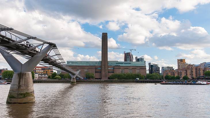 A bridge atop the River Thames leading to a building with a chimney A bridge atop the River Thames leading to a building with a chimney