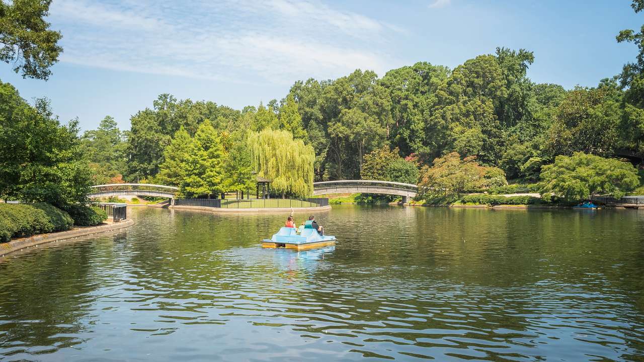 A lake with a pedal boat on it surrounded by trees