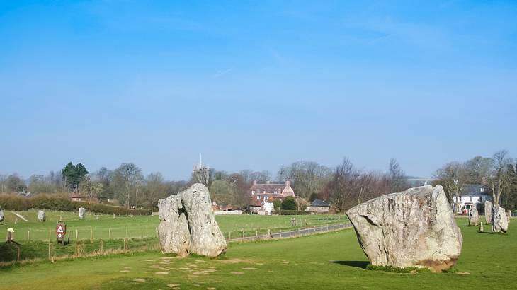 Ring of ancient standing stones surrounded by grass on a clear day