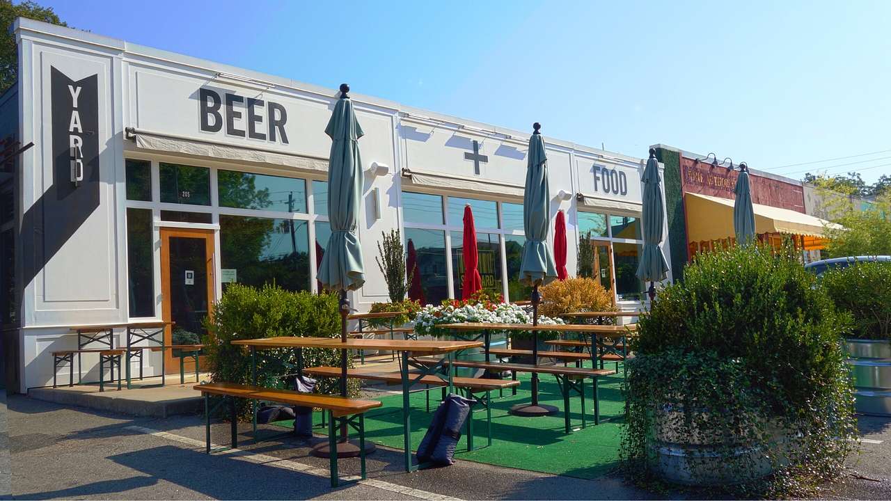 The front of a restaurant with a patio and a sign that says "Yard Beer + Food"