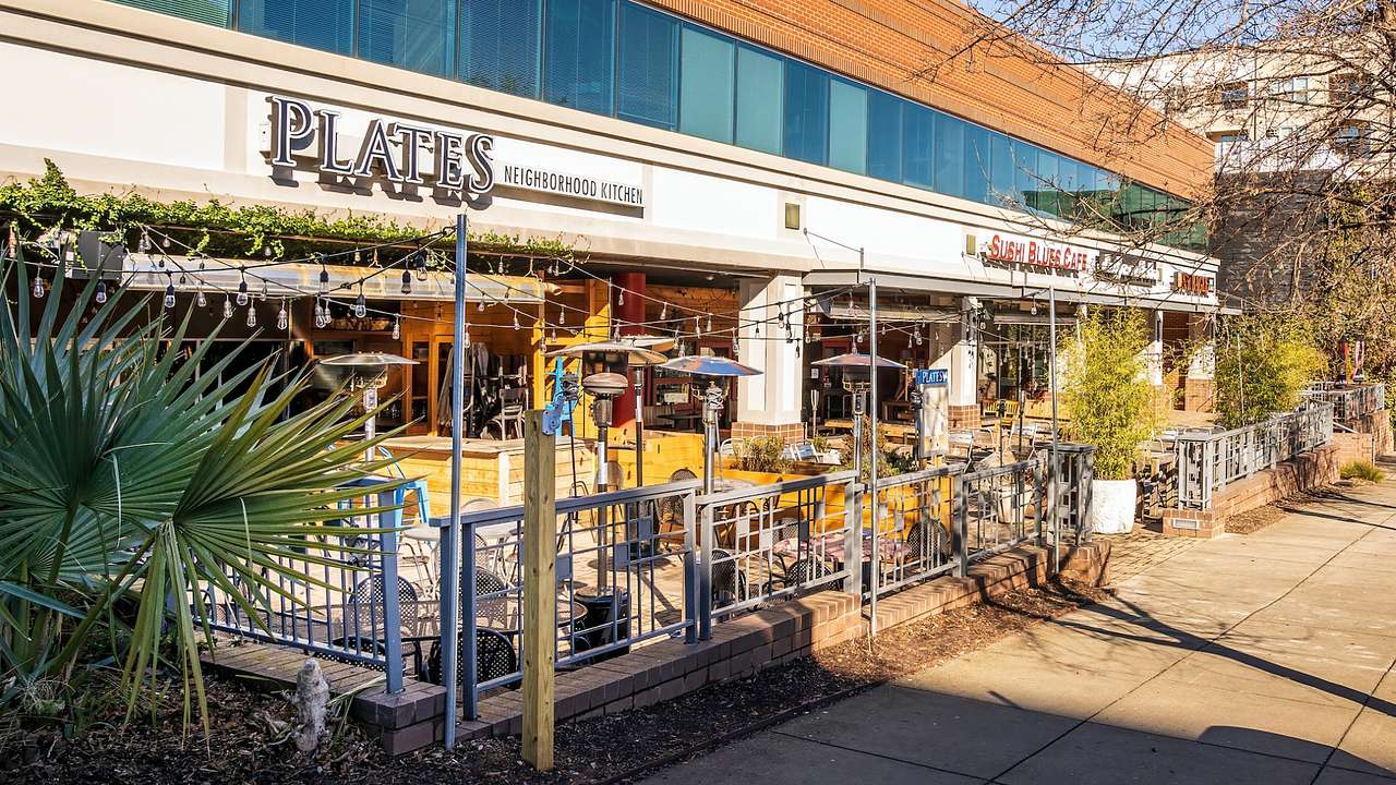 The exterior of a restaurant with a patio and a "Plates Neighborhood Kitchen" sign