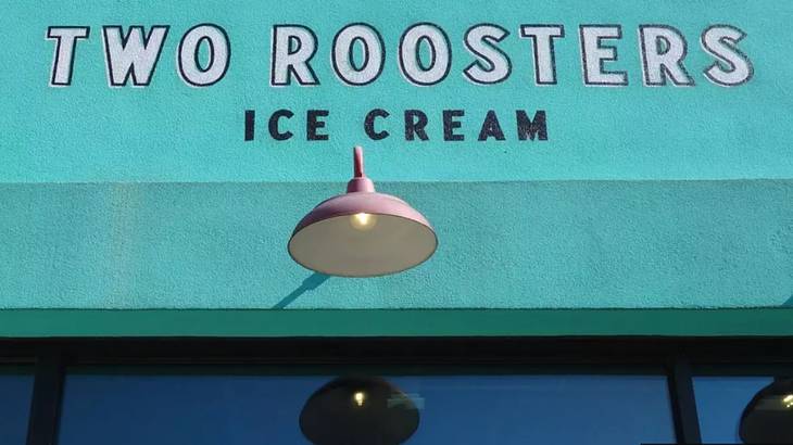 The front of a shop with a turquoise sign that says "Two Roosters Ice Cream"