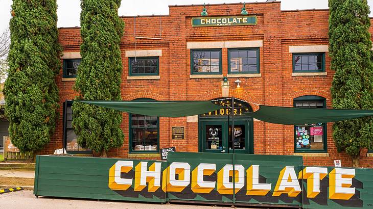 A red brick building with a large green and yellow sign that says "Chocolate"