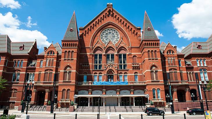 A maroon-colored cathedral-like building with multiple windows and street lamps