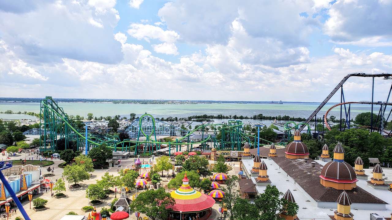 Aerial view of an amusement park showing rides, colorful stalls, and the sea