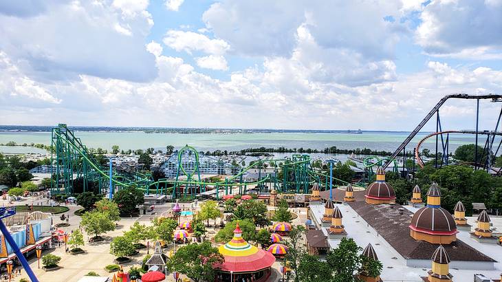 Aerial view of an amusement park showing rides, colorful stalls, and the sea