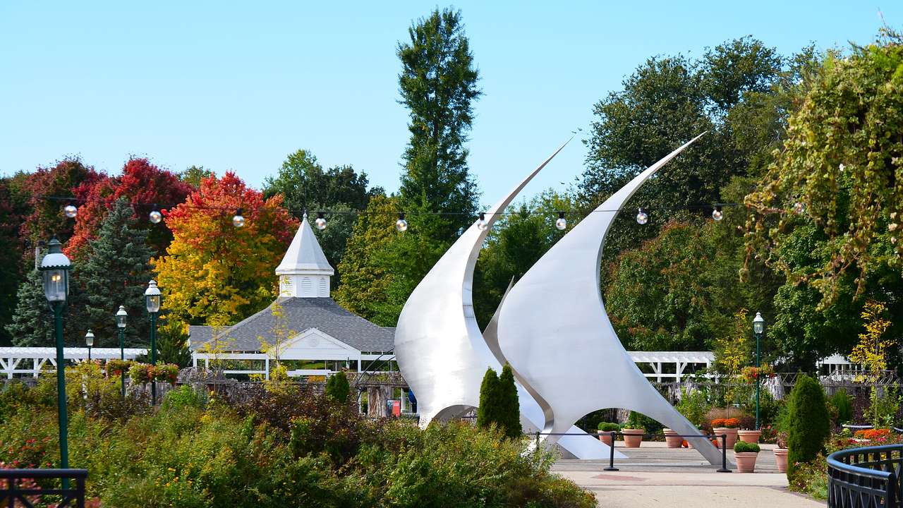A garden filled with bushes and trees, a gazebo, and white sail-shaped art structures
