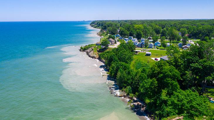 A long coastline with blue-green waters alongside a line of trees and a small town