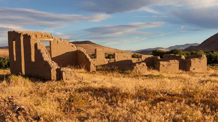 Old ruins and dry grass under a partly cloudy sky