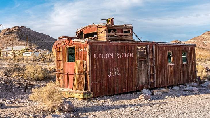 Abandoned red wagon in a deserted area with a partly cloudy sky behind