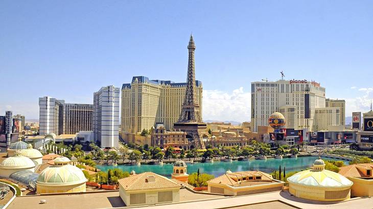 An Eiffel-tower replica surrounded by tall hotel buildings overlooking a blue pool