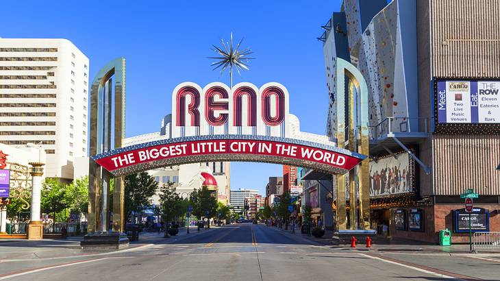 A road with a white and red sign reading "Reno, The Biggest Little City in the World"