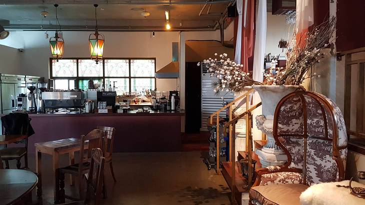 The interior of a cafe with a counter at the back and chairs and tables in front