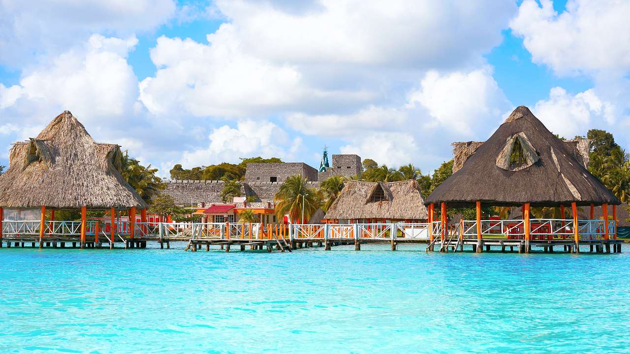 Colorful huts over clear turquoise water on a partly cloudy day