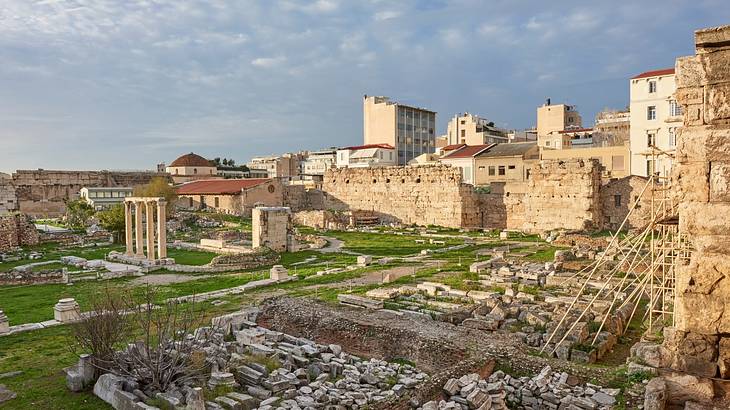 Ancient Roman library ruins with city buildings at the back and clouds above