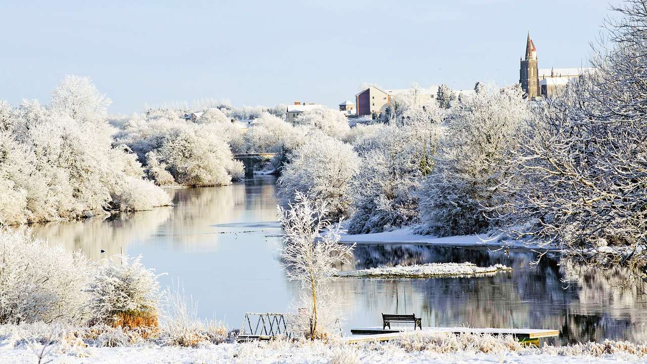 An icy river surrounded by snow-covered trees and buildings