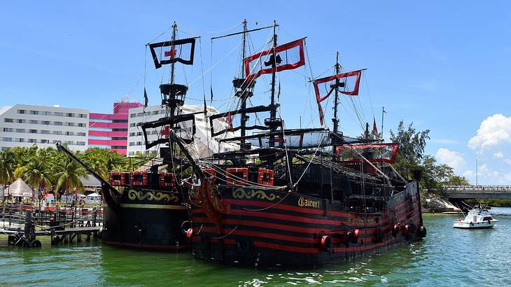 Two red and black pirate ships on the water under a blue sky