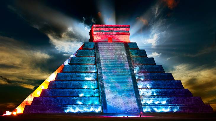 A Mayan pyramid lit up by illuminations from a light show at night