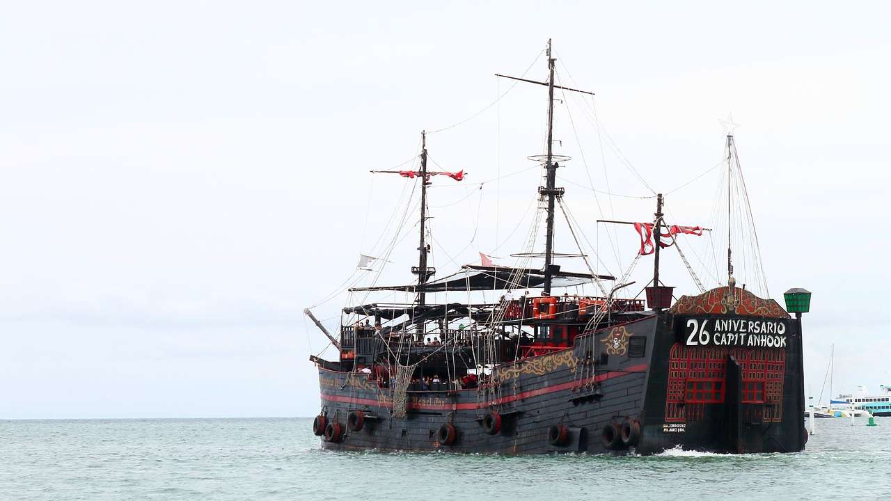 A pirate-themed ship painted in red and black sailing across the sea