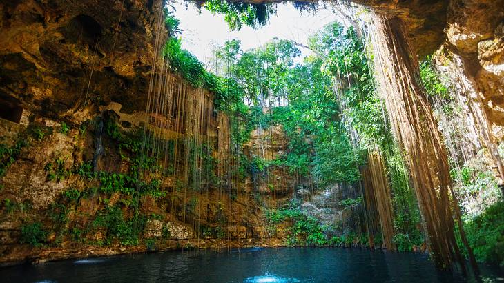 A subterranean lagoon with rock walls and greenery surrounding and sky visible above