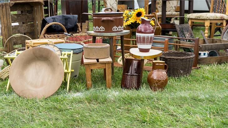 Market items, like vases, dishes, furniture and crates, on a grassy floor