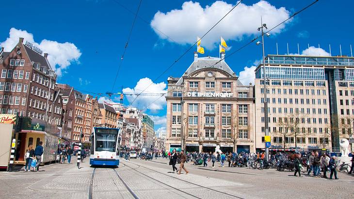 A square with a train surrounded by old buildings with many windows