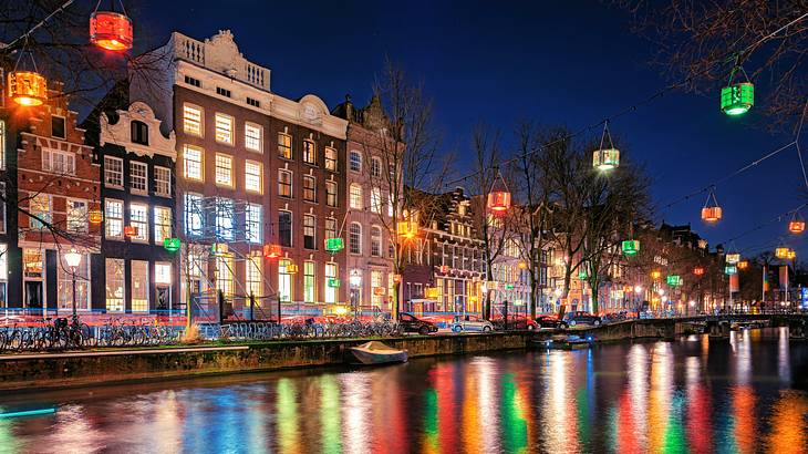 A canal next to buildings with different colored lights illuminating the area