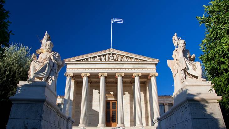 Two stone monuments in front of a grand building entrance on a sunny day Two stone monuments in front of a grand building entrance on a sunny day