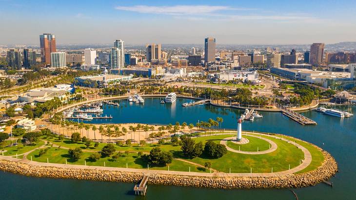 An aerial shot of a coastal city with buildings, greenery, and a lighthouse