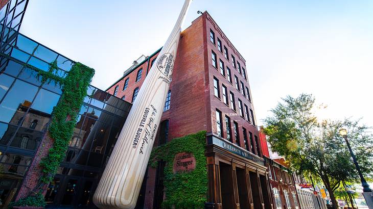 Looking up at a giant baseball bat leaning on the side of a brown building